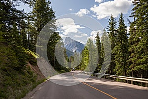 Highway in mountains. Transportation. Landscape rocks, sunny sky with clouds, Banff, Alberta, Canada