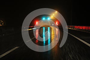 Highway at night in the rain with colored lights reflections on the asphalt