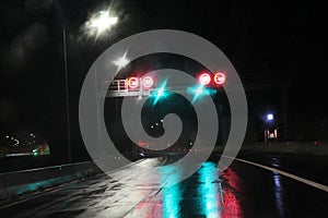 Highway at night in the rain with colored lights reflections on the asphalt