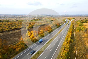 Highway, road in autumn in leaf fall. Cars drive on asphalt road. Landscape from drone. Autumn Highway, Ukraine