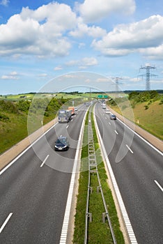 Highway, road and cars with landscape for travel with clouds, blue sky and environment in Denmark. Aerial, motor and