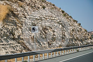 Highway road in the mountains with a speed camera limit sign on the side of the road