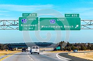 Highway road sign to Hamptons New York in a blue sky day