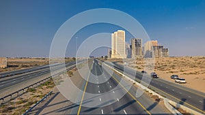 Highway roads with traffic timelapse in a big city from Ajman to Dubai before sunset. Transportation concept.