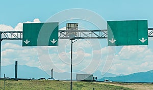 Highway signs next to highway with mountains in the background, rural transportation concept