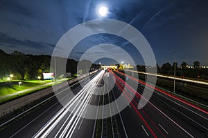 Highway traffic light trails at night under moonlight