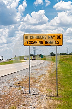 Highway warning sign about hitchhikers that might escaping inmates photo