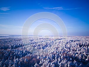 Highway through the winter forest. Aerial view on road and river on background. Blue sky