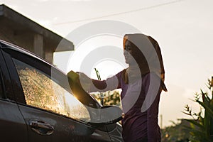 Hijab Woman car washing with yellow sponge  washing her car  in front of the house