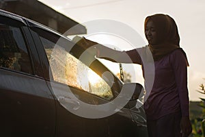 Hijab Woman car washing with yellow sponge  washing her car  in front of the house