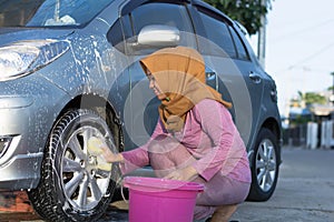 Hijab woman cleaning car tires at outdoors area