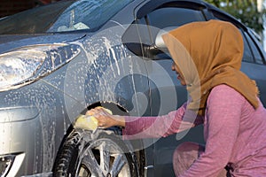 Hijab woman cleaning car tires at outdoors area