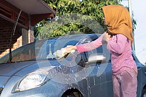 Hijab woman cleaning the windshield at outdoors area