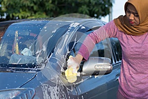 Hijab woman cleaning the windshield at outdoors area