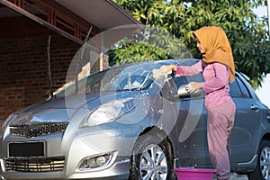 Hijab woman cleaning the windshield at outdoors area