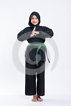 Hijab women wearing pencak silat uniforms with green belts perform hand gestures of respect