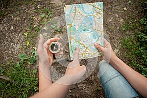 Hike. The teenager holds a map and a compass in his hand. An adult`s hand points the way