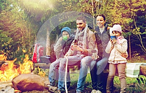 Happy family sitting on bench at camp fire