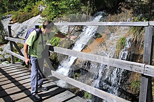 Hiker admires the beautiful waterfall in High Tatras