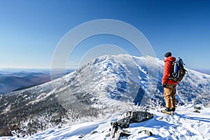 hiker admiring view from snowy mountaintop, clear sky