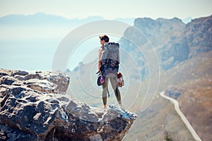 Hiker, adventure and mountain top of a woman in rock climb, view and backpacking in nature. Active female traveler on