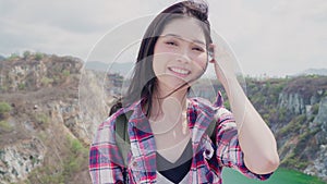 Hiker Asian backpacker woman feeling happy smiling to camera on top of mountain, Female enjoy her holidays on hiking adventure