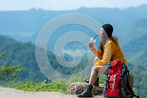 Hiker asian woman sitting and drinking coffee for relax and rest on mountain. Female adventure backpack and trips camping on hike photo