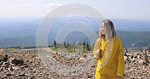 Hiker with backpack hiking on top of a mountain. Girl in a yellow raincoat on top of a mountain