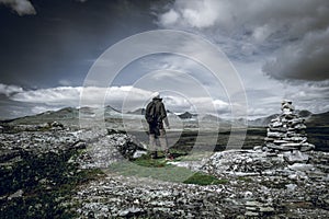 Hiker with backpack looking towards a beautiful mountain scenery