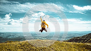 Hiker with backpack raising hands jumping on the top of a mountain - Successful man with arms up enjoying victory