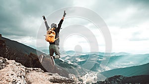 Hiker with backpack raising hands jumping on the top of a mountain - Successful man with arms up enjoying victory