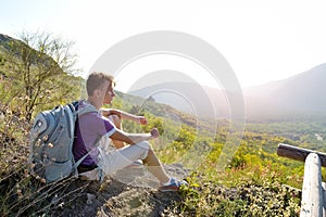 Hiker with backpack relaxing on a path of mountain