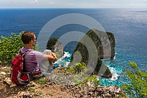 Hiker with backpack sitting on the top of the mountain and enjoy view
