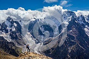 Hiker with backpack standing on mountain top and enjoying scene