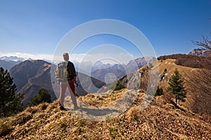 Hiker with backpack standing on top of a mountain and watching the landscape.