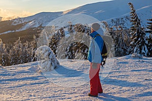 Hiker, with backpack, stands on the mountain ridge during dawn