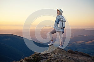 Hiker with backpack in the top of the mountain. Young girl walking in the mountains during sunset. Mountains and people.