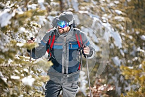 Hiker with backpack trekking in mountains. Cold weather, snow on