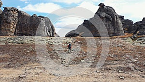 Hiker With Backpack And Trekking Sticks Climbs To Top Of A Mountain With Rocks