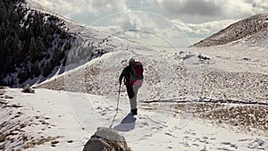 Hiker With Backpack Walking On A Mountain Ridge, Covered With Deep Snow