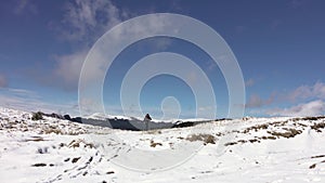 Hiker With Backpack Walking On A Mountain Ridge, Covered With Deep Snow