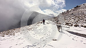 Hiker With Backpack Walking On A Mountain Ridge, Covered With Deep Snow