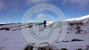 Hiker With Backpack Walking On A Mountain Ridge, Covered With Deep Snow