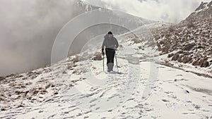 Hiker With Backpack Walking On A Mountain Ridge, Covered With Deep Snow