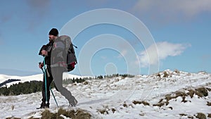 Hiker With Backpack Walking On A Mountain Ridge, Covered With Deep Snow