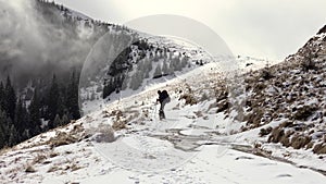 Hiker With Backpack Walking On A Mountain Ridge, Covered With Deep Snow