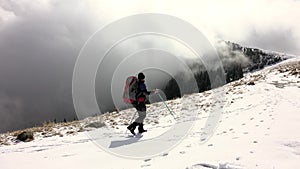 Hiker With Backpack Walking On A Mountain Ridge, Covered With Deep Snow