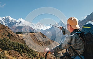 Hiker backpacker man using trekking poles pointing to Everest 8848m mountain during high altitude Acclimatization walk. Everest
