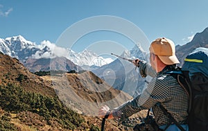 Hiker backpacker man using trekking poles pointing to Everest 8848m mountain during high altitude Acclimatization walk. Everest photo