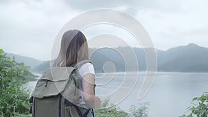 Hiker backpacker woman on hiking adventure feeling freedom walking in forest near lake in rainy day.